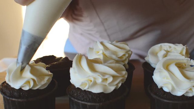 girl puts a delicious white cream on mafin