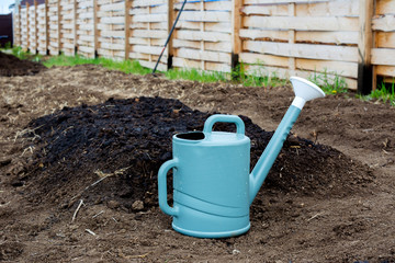 the watering can is next to the watered bed.