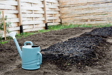 the watering can is next to the watered bed.