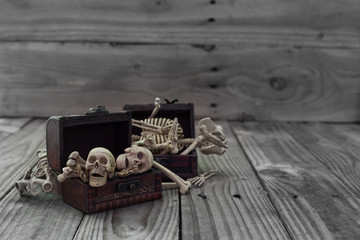 Skeleton pirate in a treasure chest and old wood floor background.