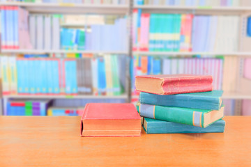 old book red - green. and heap treatise in school library on wooden table.  blurry bookshelves background. education learning concept with copy space add text