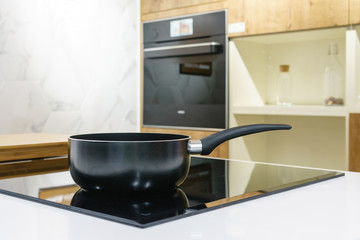 Close-up of stainless steel cooking pot and pan on induction hob in modern kitchen. modern kitchen...