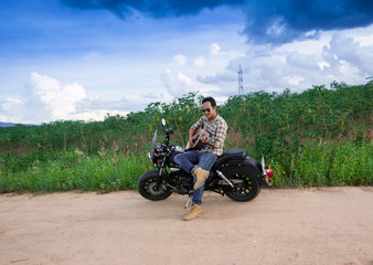 Fototapeta premium Men Play guitar with motorcycle in the countryside 