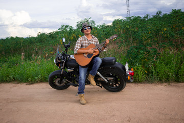 Men  Play guitar with  motorcycle in the countryside

