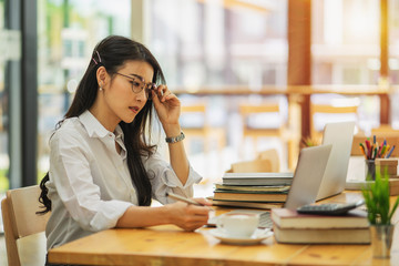 Young woman sitting at cafe working on laptop