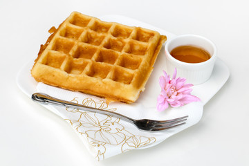 Waffle with honey on white table.Fresh homemade waffles serving on a plate with blossom and honey. Romantic breakfast.
