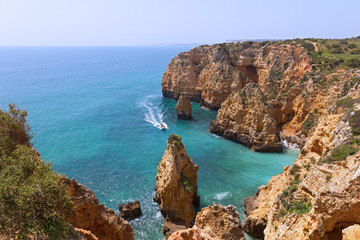 Sightseeing of sandstone cliffs and grottoes by boat is one of popular pastime activity in Lagos, Portugal. Algarve coastline on a sunny morning in spring.