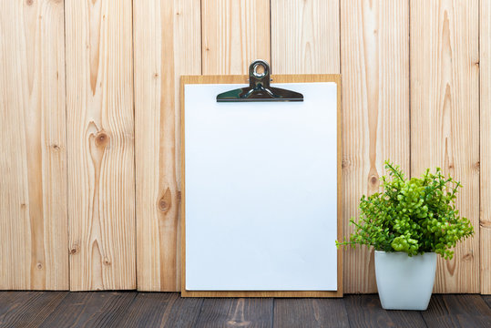 Clipboard blank white paper sheet with little decoration tree in white vase on wooden background, memo template design