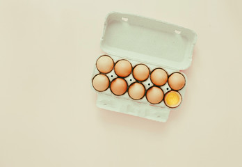Chicken egg half broken among eggs egg carton yellow background top view flat lay Vintage toned