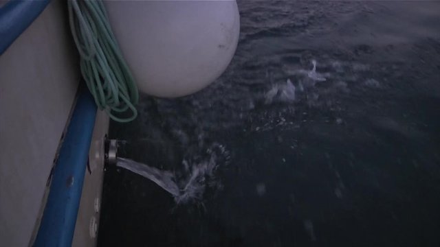 Close up looking down at a fishing boat bilge as water flows out into the sea while in motion
