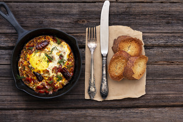 Shakshuka dish in a pan on a wood vintage rustic background. Top view composition