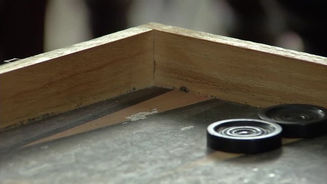Close up roll of the dice beside checkers on a board of backgammon