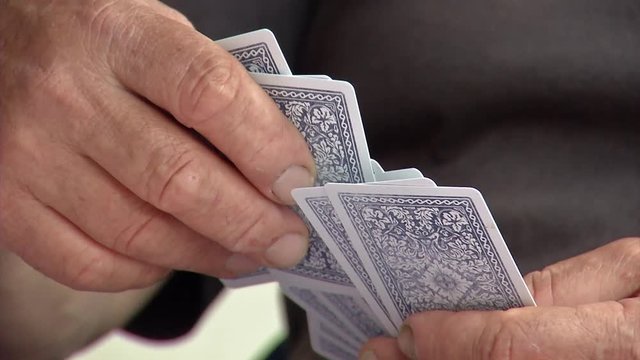 Close up of hands picking up playing cards and added them to his hand