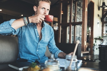 Young entrepreneur working on business project in city cafe, drinking coffee