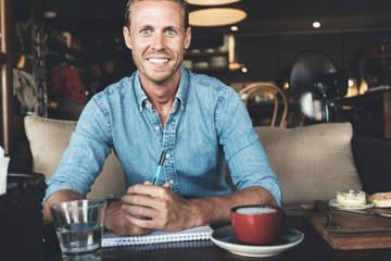 Portrait of happy entrepreneur working on his business idea in city cafe