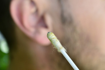hygiene and body care concept. man using cotton stick for cleaning ear wax