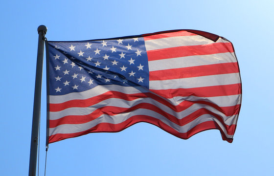 American flag with blue sky and flare sunlight