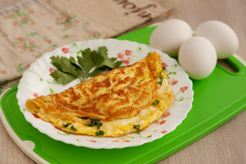 French omelette on a saucer. Omelet from eggs, grated cheese and parsley. A dish of chicken eggs for breakfast.