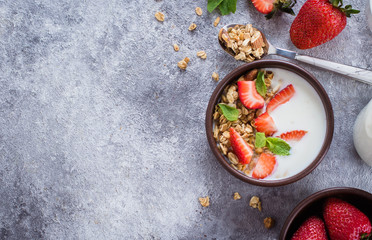 Food Background. Breakfast with yogurt, granola of muesli and strawberries on gray concrete table background. Healthy Diet Food Concept. Top view, copy space, flat lay