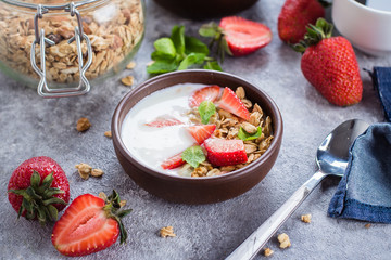 Breakfast with yogurt, granola of muesli and strawberries on gray concrete table background. Healthy Vegan Clean Diet Food Concept. Top view, copy space, flat lay