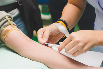 The nurse takes the patient's blood with a syringe.