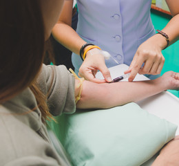 The nurse takes the patient's blood with a syringe.