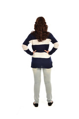 full length portrait of girl wearing striped blue and white jumper and jeans. standing pose  facing away from the camera, on white studio background