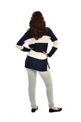 full length portrait of girl wearing striped blue and white jumper and jeans. standing pose  facing away from the camera, on white studio background