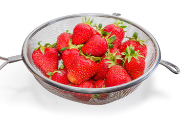 Washed strawberries in stainless steel sieve on a white background