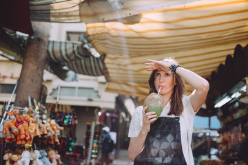 Fototapeta na wymiar Young woman drinking coconut milk at traditional bazaar in Dubai, UAE