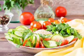 Fresh slices of cucumbers, tomatoes and parsley leaves on a plate on a wooden table