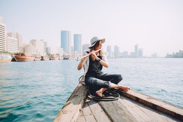 oung beautiful woman sitting at boat and playing the flute © TY Studio