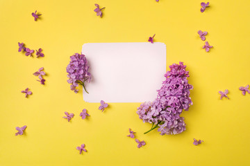 Fresh branches of purple lilac and flowers on a bright yellow background. Greeting card. Mockup for positive ideas. Empty place for inspirational, emotional, sentimental text or quote.