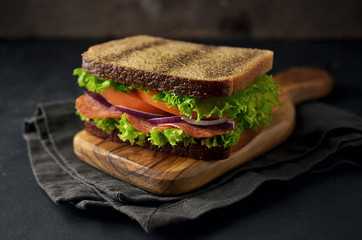Wholemeal sandwich with vegetables on cutting board