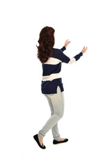 full length portrait of girl wearing striped blue and white jumper and jeans. standing pose  facing away from the camera, on white studio background