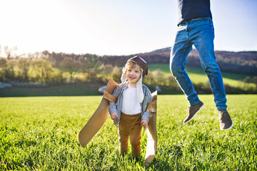 Happy toddler boy playing outside with father in spring nature.