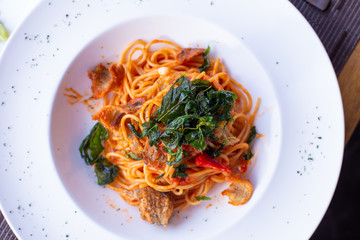 A dish of pasta with red spicy sauce and fried Snakeskin gourami fish on top with deep fried basil in Thai style.