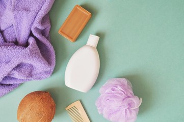 Bath products flat lay photo/ Purple terry towel, tar soap, shampoo bottle, coconut, wooden comb and purple sponge. Top view photo organic bath products