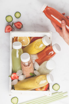 Variety colorful smoothies or juices bottles from berries, fruits and vegetables in white wooden box. Detox program, healthy lifestyle concept.