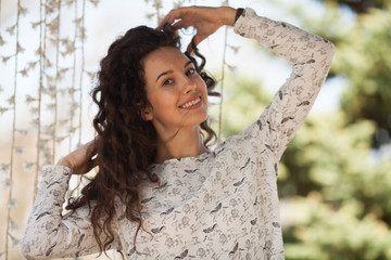 Portrait of happy young woman with curly hair on city background.