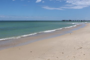 Fototapeta na wymiar Endless white sand beach with pier In Glenelg, South Australia