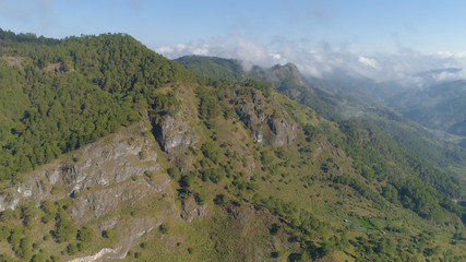 Fototapeta na wymiar Aerial view of mountains covered forest, trees in clouds. Cordillera region. Luzon, Philippines. Slopes of mountains with evergreen vegetation. Mountainous tropical landscape.