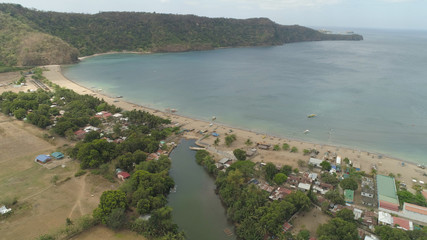 Aerial view of coast with beach in blue lagoon. Philippines, Luzon. Coast ocean with tropical beach, turquoise water. Tropical landscape in Asia.