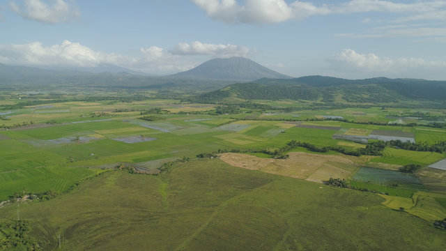 Mountain valley with farmland, rice terraces near mount Iriga. Aerial view mount with green tropical rainforest, trees, jungle with sky. Philippines, Luzon. Tropical landscape