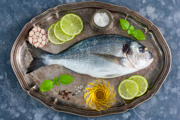Fresh raw Dorado fish on a metal tray with ingredients for cooking, top view, horizontal