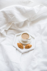 Early morning breakfast in bed, coffee and croissant on the tray