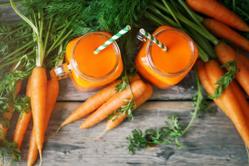 Fresh Carrot and carrot juice on Wooden Table in Garden. Vegetables Vitamins Keratin. Natural Organic Carrot lies on Wooden background.