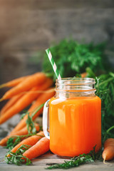 Fresh Carrot and carrot juice on Wooden Table in Garden. Vegetables Vitamins Keratin. Natural Organic Carrot lies on Wooden background.