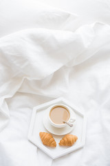 Early morning breakfast in bed, coffee and croissant on the tray