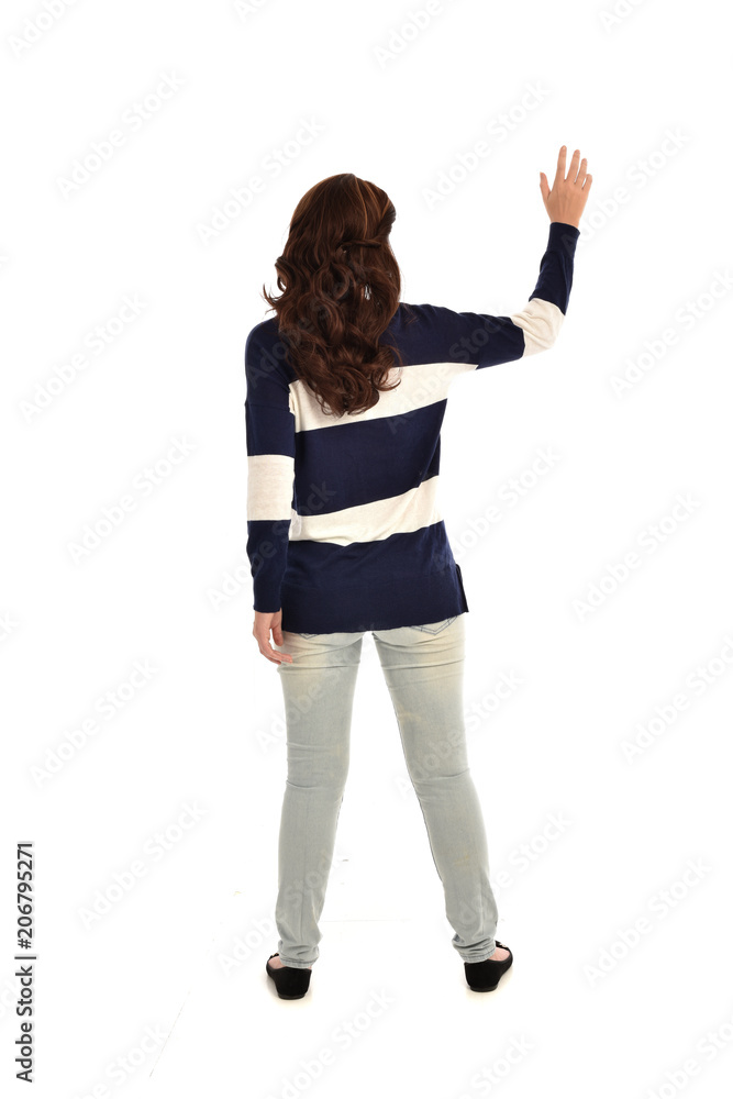 Canvas Prints full length portrait of girl wearing striped blue and white jumper and jeans. standing pose  facing away from the camera, on white studio background